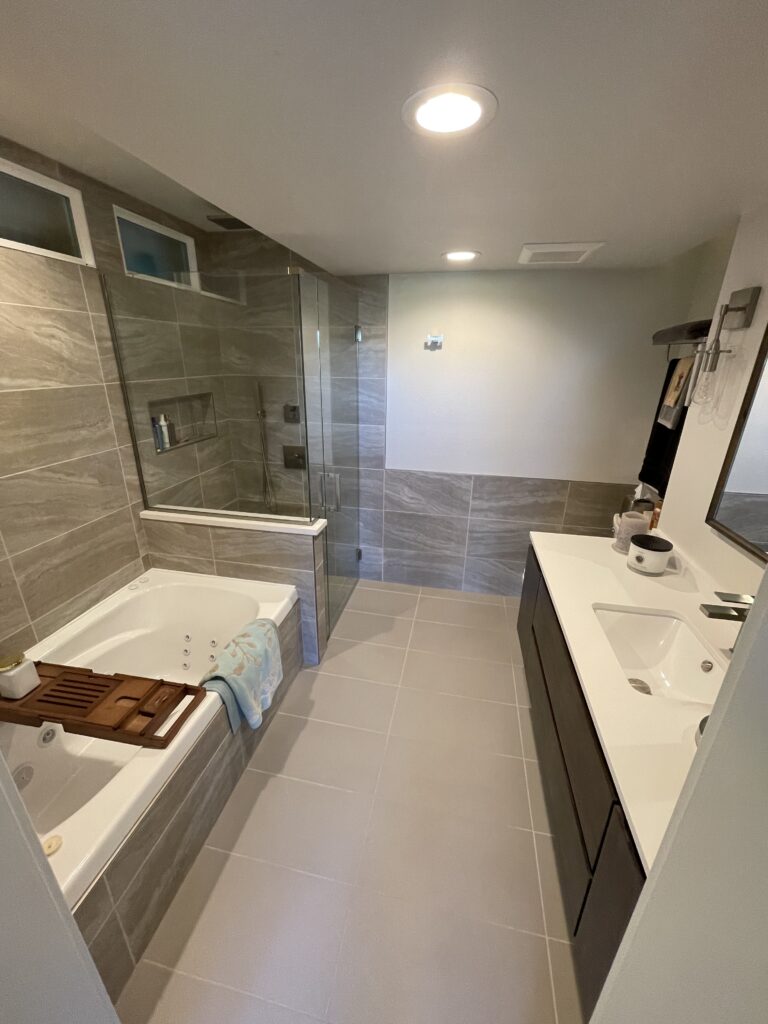 Custom bathroom remodel with curb less walk-in shower, floating vanity, tub deck, and niches by Eckert Renovations in Broomfield Colorado