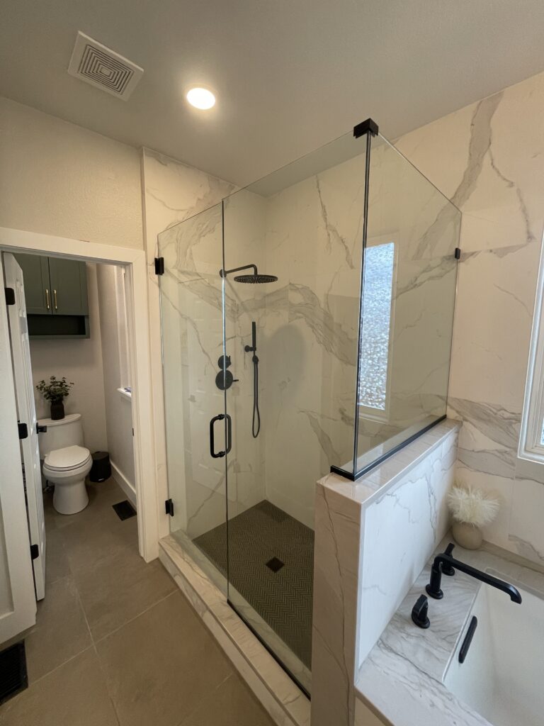 Custom tiled walk-in shower with niche and glass enclosure by Eckert Renovations in Arvada Colorado