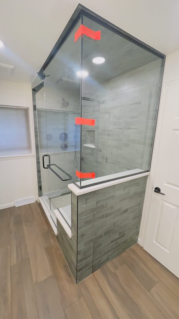 Custom steam shower with large format tile, built-in bench, and glass enclosure by Eckert Renovations in Lafayette Colorado